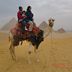 Kleinfamilie auf einem Kamel vor den Pyramiden von Giza