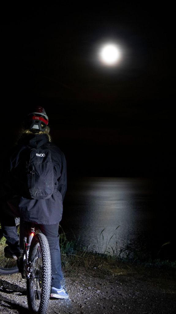 Mit dem E-Bike bei Vollmond, der sich im Meer an der Costa dei Gabbiani spiegelt